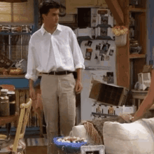 a man in a white shirt and khaki pants is standing in front of a refrigerator in a living room