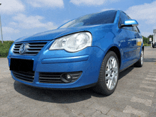 a blue volkswagen is parked on a brick driveway