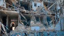 a man stands in front of a destroyed building with the number 3 on the wall