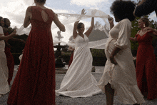 a bride in a white dress is surrounded by bridesmaids in red dresses