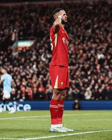 a soccer player wearing a red jersey that says fly emirates