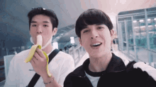 two young men are eating a banana together and smiling for the camera