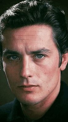 a close up of a man 's face with blue eyes and black hair