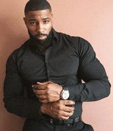 a man with a beard is wearing a black shirt and black pants