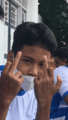 a young man wearing a face mask makes a middle finger gesture