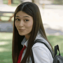 a girl wearing a white shirt and red tie has a backpack