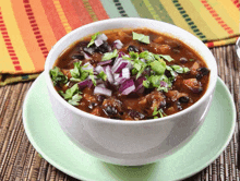 a bowl of chili sits on a green plate