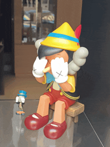 a pinocchio figurine sits on a wooden bench