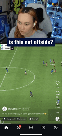 a woman is watching a soccer game on a cell phone and asking if this is not offside