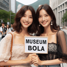 two women hold a sign that says museum bola