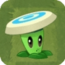 a green plant with a frisbee on its head is sitting in the grass .