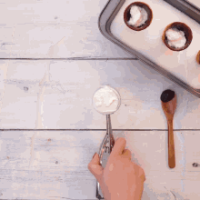 a scoop of ice cream sits on a table next to a tray of ice cream cones and a wooden spoon