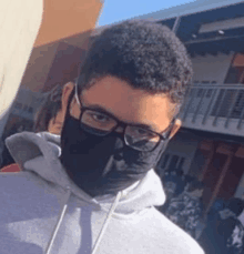 a young man wearing glasses and a black face mask .