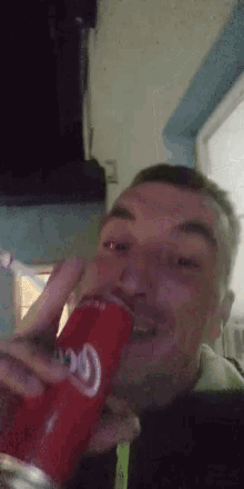 a man is drinking a can of coca cola with a straw