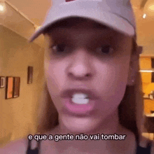 a woman wearing a hat is making a funny face and says e que a gente nao vai tombar .