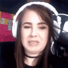 a woman wearing headphones and a choker is making a face .