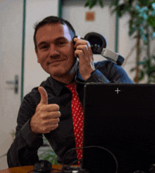 a man is giving a thumbs up in front of a laptop