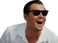 a man wearing sunglasses and a white shirt is laughing with his mouth wide open .