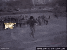 a black and white photo of a man running in front of a flock of birds .