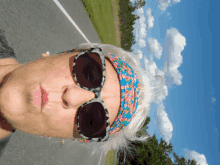 a woman wearing sunglasses and a headband is standing on the road