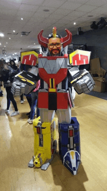 a man in a robot costume is standing on a wood floor .