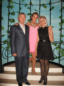 a woman in a pink dress is posing with her parents