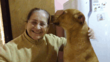 a woman is holding a dog in front of a refrigerator with a picture of a man on it