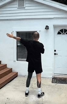 a man with a tattoo on his leg is standing in front of a white house