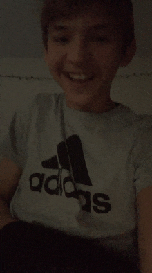 a young boy wearing an adidas t-shirt is smiling