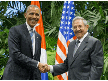 a man in a suit shakes hands with another man in front of a flag