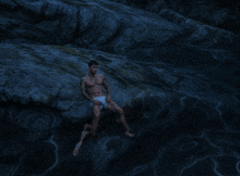 a man sitting on a rock in the water