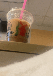 a plastic cup of coffee with a pink straw and a windmill on it