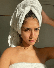 a woman wrapped in a white towel has a towel wrapped around her head