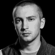 a black and white photo of a young man with a shaved head