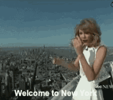 a woman in a white dress is standing on top of a building with the words welcome to new york below her