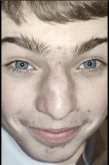 a close up of a young man 's face with blue eyes and a beard