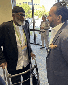 a man with a lanyard around his neck that says ' elderly ' on it talks to another man