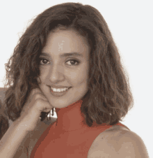 a woman with curly hair wearing a red turtleneck