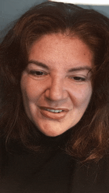 a woman with long hair is smiling and wearing a black shirt