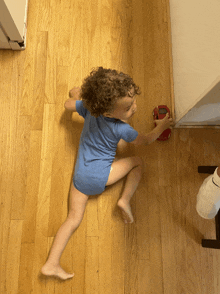 a little boy in a blue shirt is playing with a red toy car on the floor