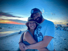 a man and a woman are hugging on the beach