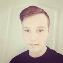 a young man with red hair and a black shirt is standing in front of a door .