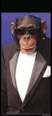 a chimpanzee wearing a tuxedo and sunglasses .