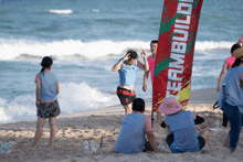 a group of people on a beach with a flag that says teambuild on it