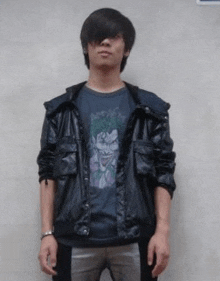 a young man wearing a black jacket and a joker t-shirt