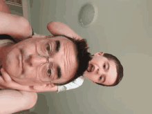 a man wearing glasses is holding a young boy on his shoulders