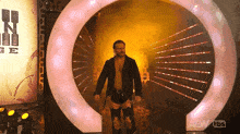 a wrestler is walking through a tunnel that says aew on it