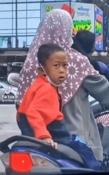 a little boy is sitting on the back of a motorcycle .