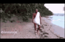 a man in a towel is walking on a beach .