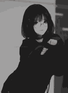 a black and white photo of a girl wearing glasses and a black shirt .